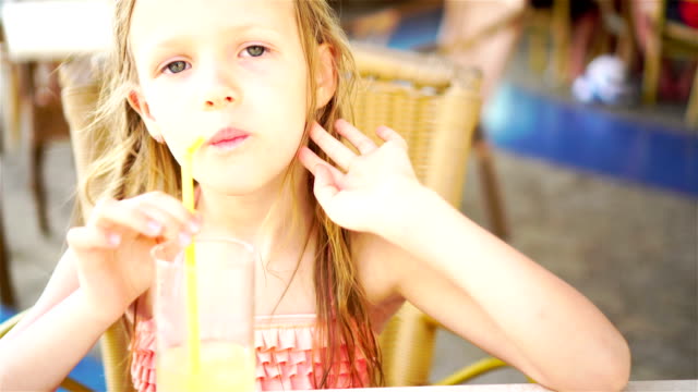 Portrait-of-cute-little-girl-sitting-by-dinner-table-anddrinking-fresh-juice