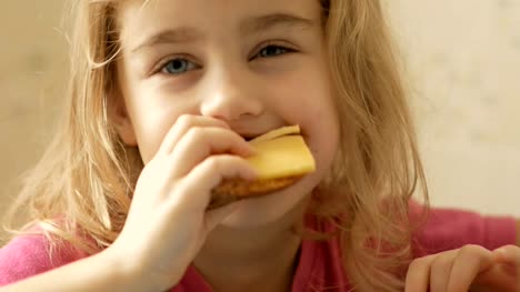 A-little-girl-is-eating-a-sandwich-with-cheese.-The-child-eats-bread-and-cheese.