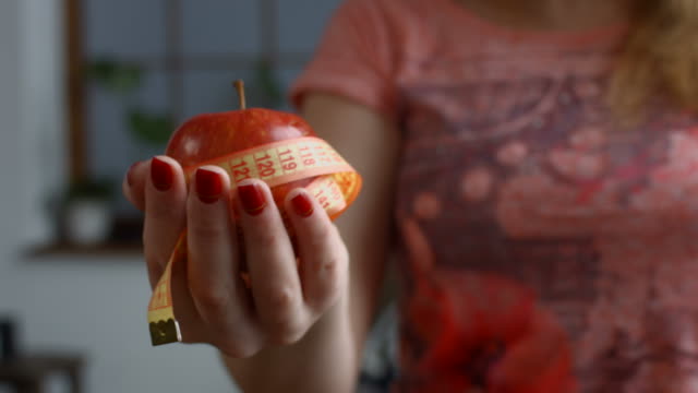 Woman-holding-fresh-apple-and-measure-tape