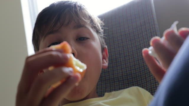 Child-relaxing-while-eating-apple-in-4K