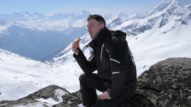 Esquiador-de-hombre-comiendo-un-Sandwich-de-almuerzo-en-la-estación-de-esquí-de-montaña
