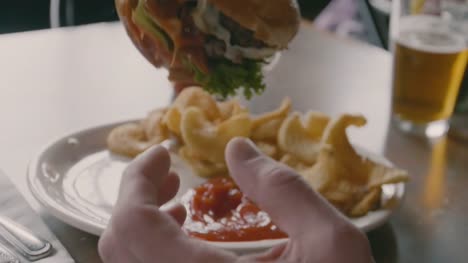 Man-taucht-doppelt-Fleisch-Patty-Burger-in-Ketchup-vor-der-Einnahme-von-großen-Bissen-Closeup