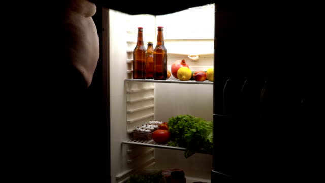 Ein-dicker-Mann-nimmt-ein-Bier-im-Kühlschrank.