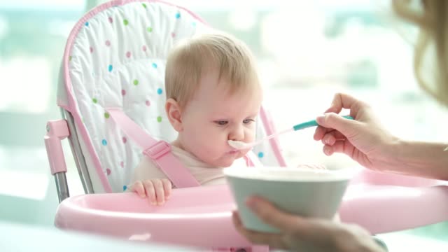 Absently-baby-not-eating-puree.-Mother-feeding-daughter.-Infant-eating-dinner