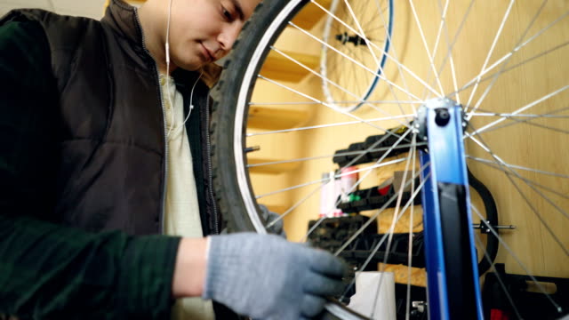 Professional-repairman-is-fixing-bicycle-wheel-spokes-straightening-them-with-special-tools-and-rotating-wheel-to-check-spokes.-Occupation-and-repair-concept.