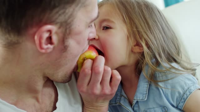 Niedliche-Mädchen-und-Vater-Apfel-beißen
