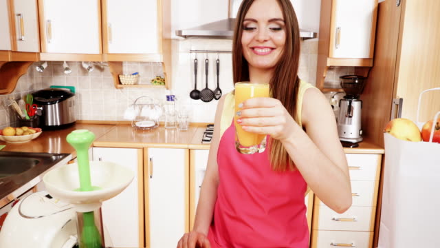 Frau-in-der-Küche-trinken-frischen-gepressten-Orangensaft-4K