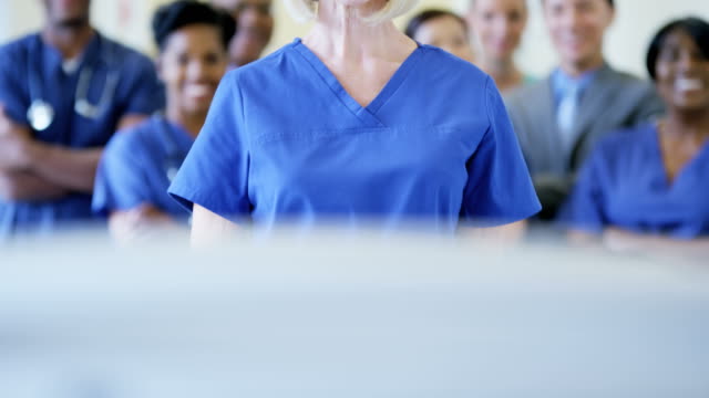 Portrait-of-female-nurse-and-team-of-staff