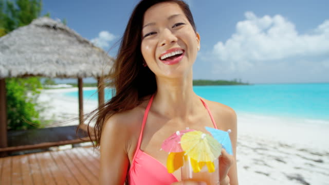 Lächelnd-ethnischen-weibliche-genießen-bunten-Cocktail-am-Strand