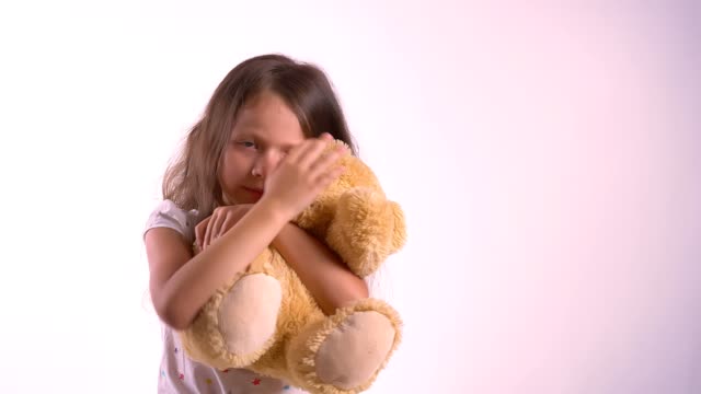 Little-cute-girl-hugging-her-plush-teddy-bear,-kid-embracing-toy,-standing-isolated-on-bright-pink-studio-background