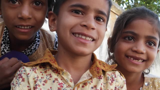 Three-Indian-kids-looking-at-the-camera-and-making-hand-gestures,-closeup-handheld