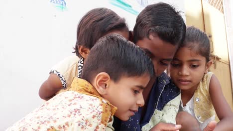 Indian-kids-sharing-a-touch-screen-phone-mobile-screen,-handheld