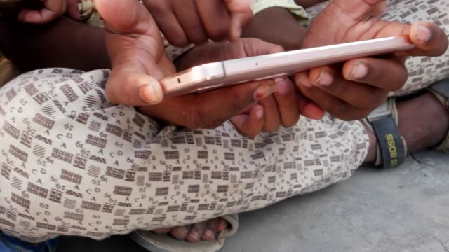Indian-kids-sharing-a-touch-screen-phone-mobile-screen,-handheld-closeup