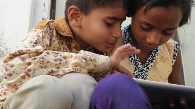 Kids-busy-working-on-a-touch-screen-tablet-and-discussing,-India