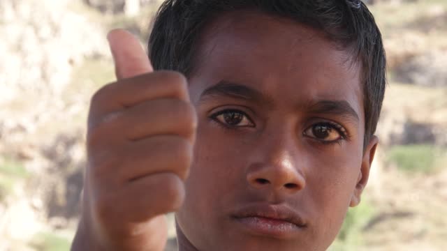 Portrait-of-a-young-Indian-boy-with-serious-look-and-thumbs-up