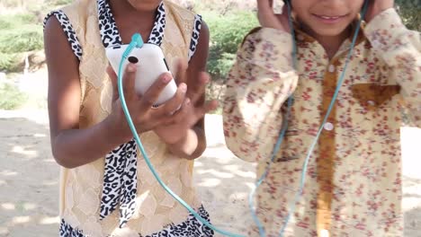 Un-niño-escuchando-música-en-auriculares-mientras-la-otra-sostiene-el-teléfono-celular-móvil