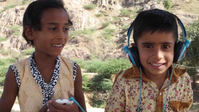 Ein-Kind-über-Kopfhörer-Musik-hören,-während-der-andere-das-Handy-mobile-hält