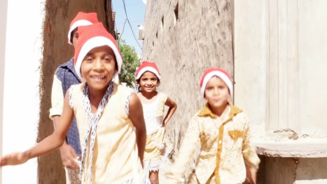 Group-of-young-friends-with-Santa-hats-running-towards-the-camera-and-making-funny-faces