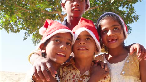 Close-up-of-kids-smiling-and-laughing-with-Santa-hats-in-summer-in-sandy-desert