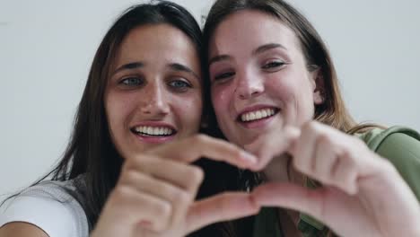 Zwei-schöne-junge-Frauen-machen-Finger-Formen-und-lachen
