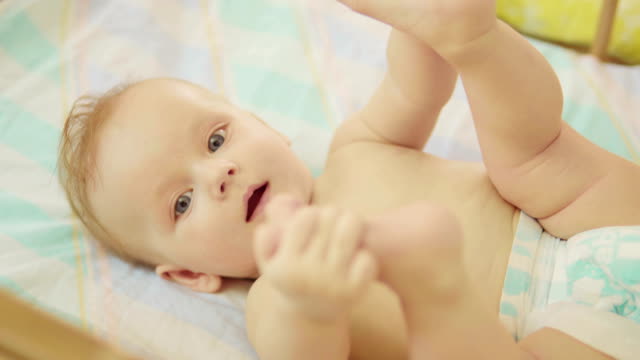 schöne-Neugeborenes-liegend-zurück-schauen-in-die-Kamera-und-lächelnd