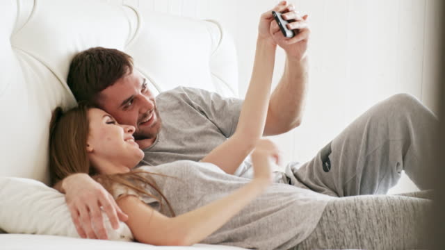 Happy-Couple-Taking-Selfie-in-Bed