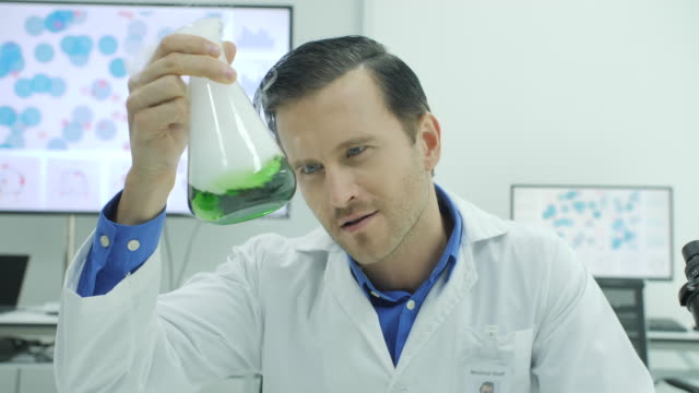 Retrato-del-loco-y-científico-loco-riendo-y-sosteniendo-el-matraz-aforado-con-líquido-verde-en-laboratorio
