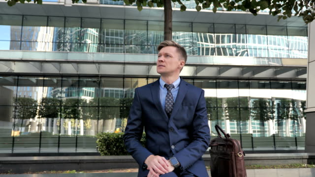 Businessman-in-Suit-Sitting-Outside-Office