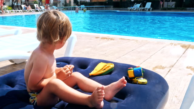 Feliz-niño-sentado-cerca-de-la-piscina