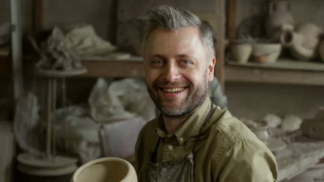 Glücklich-männlichen-Artisan-posiert-in-der-Keramikwerkstatt