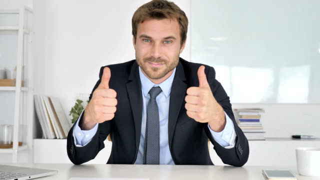 Thumbs-Up-by-Businessman-Looking-at-Camera-in-Office