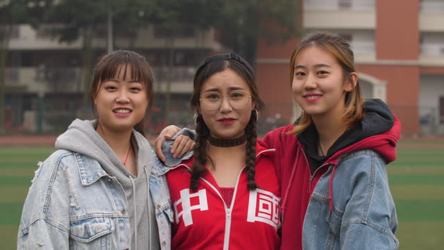 Drei-glückliche-asiatische-College-Mädchen-Lächeln-in-die-Kamera