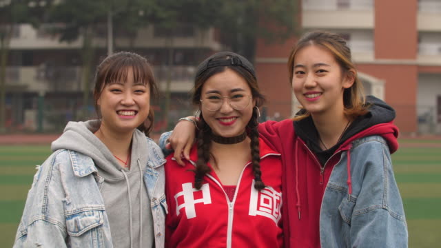 Drei-glückliche-asiatische-College-Mädchen-Lächeln-in-die-Kamera
