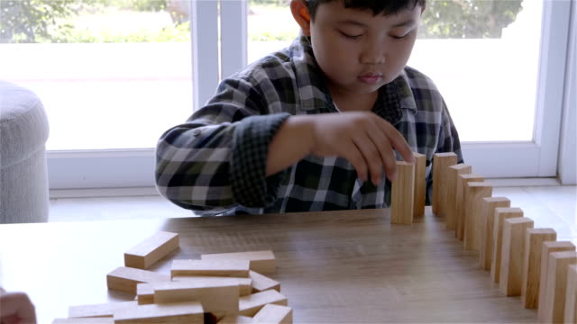 Chico-asiatico-jugando-con-juego-de-bloques-de-madera-en-casa.