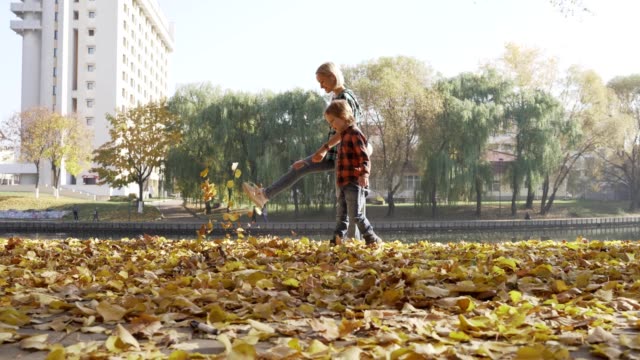 Joven-madre-divirtiéndose-con-su-hijo-en-el-Parque-otoño-en-día-soleado