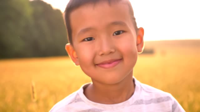 Shining-vibes-around-portrait-of-happy-asian-kid-in-sun-lights-on-wheat-field-on-countryside