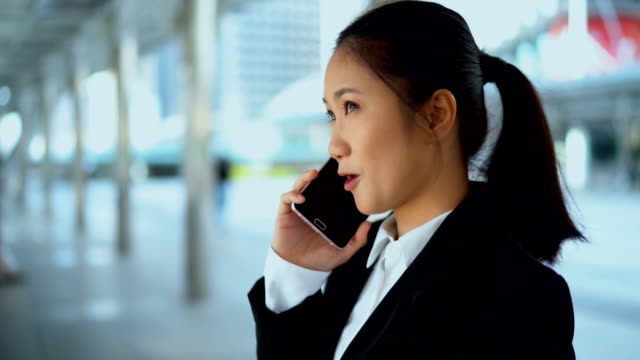 Hübsche-Geschäftsfrau-im-Gespräch-mit-Smartphone-bei-Outdoor-Büro