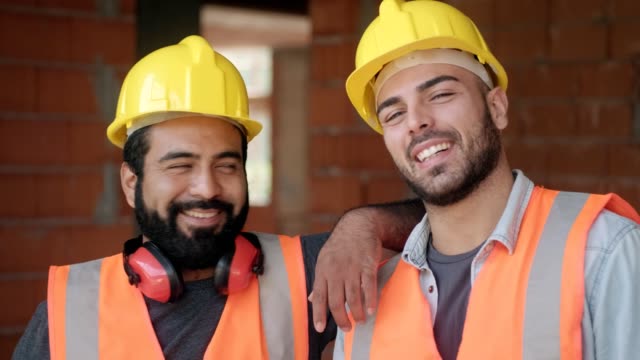 Glückliche-Bauarbeiter-lächelnd-in-die-Kamera-im-Neubau