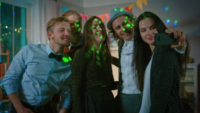 Glückliche-Gruppe-von-jungen-Leuten-unter-kollektiven-Selfie-auf-wilde-Hausparty.-Neon-Licht,-Disco-Kugel-und-lustige-Kostüme.