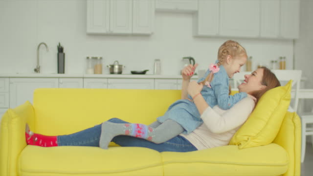 Carefree-mom-and-daughter-having-fun-on-sofa