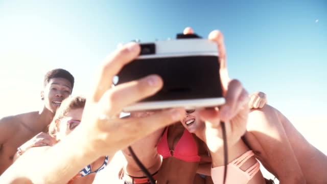 Group-of-friends-taking-a-group-selfie-on-a-beach