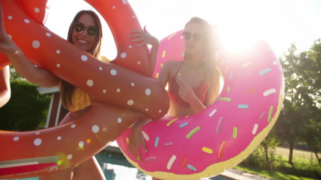 Girls-joking-around-with-novelty-pool-inflatables-with-sunflare