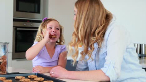 Little-girl-having-milk-and-cookies-with-her-mother