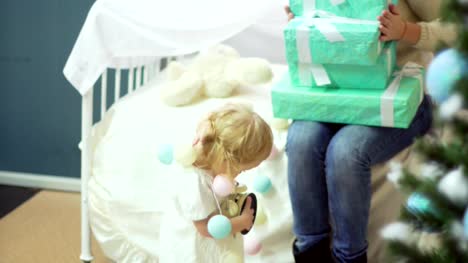 Glückliche-junge-Mutter-mit-ihrem-süßen-Baby-halten-verziert-Boxen-mit-Geschenken