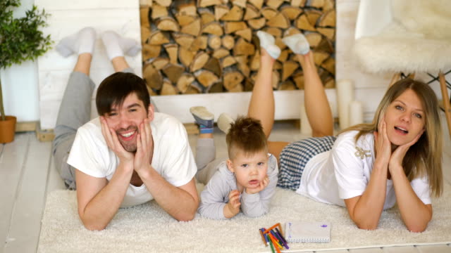 Portrait-of-a-lovely-family-posing-and-smiling-on-floor-in-their-living-room