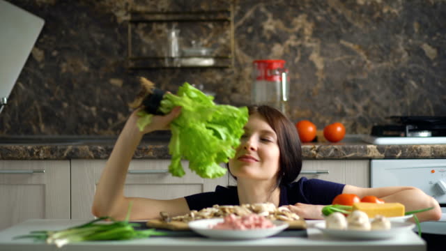 schöne-lächelnde-Frau-Koch-spielen-mit-Gemüse-auf-dem-Tisch-in-der-Küche-zu-Hause