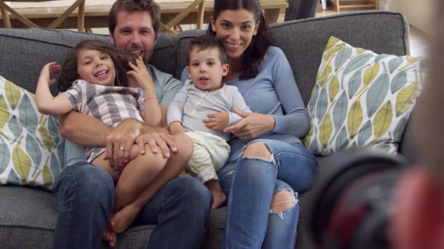 Lächelnde-Familie-sitzen-auf-Sofa-zu-Hause-mit-Foto-aufgenommen