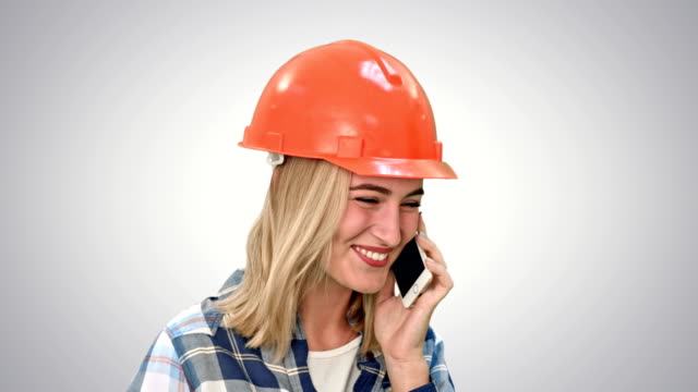 Schöne-weibliche-Ingenieur-in-Bauarbeiterhelm-Aufruf-via-Handy-auf-weißem-Hintergrund