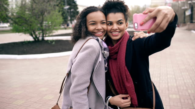 Zwei-niedliche-afroamerikanische-Frau-nehmen-Selfie-mit-Einkaufstüten-und-lächelnd.-Freunden-haben-Spaß-nach-dem-Besuch-der-Mall-Verkauf.