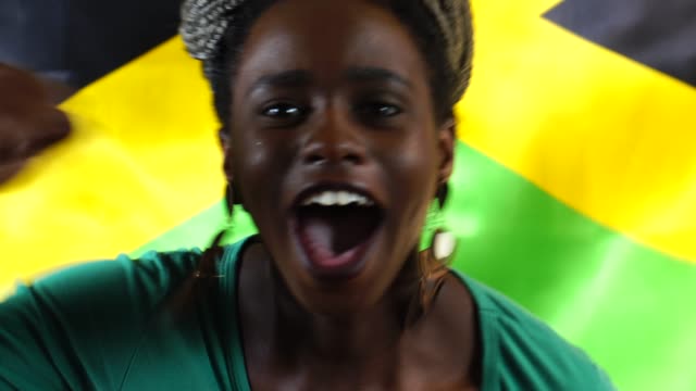 Jamaikanische-junge-schwarze-Frau-feiert-mit-Jamaika-Flagge
